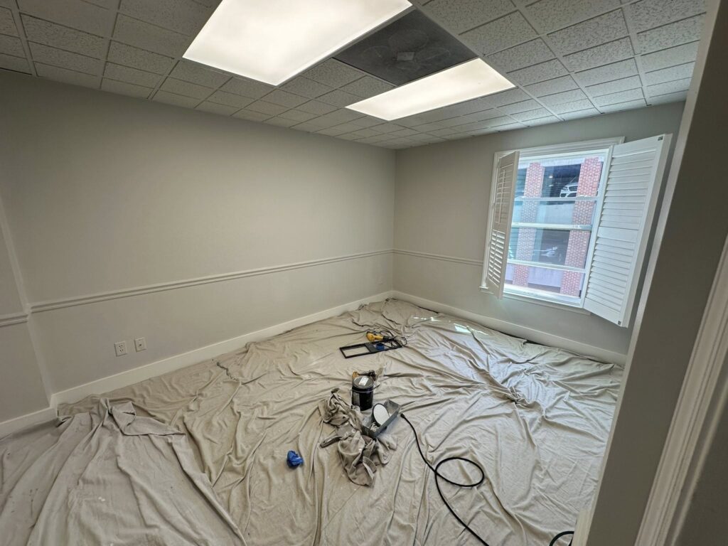 Empty room with freshly painted walls, covered floor, and tools for home improvement, illustrating BisonWorks' commitment to quality renovations.