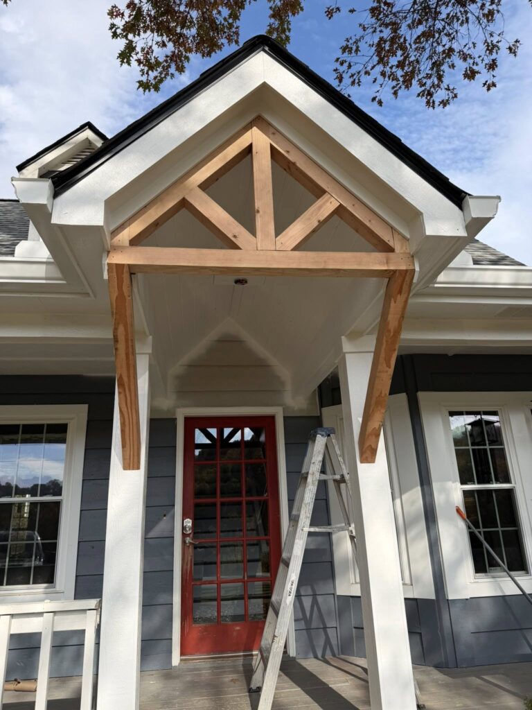 Front porch with wooden framework above a red door, showcasing ongoing roofing and home improvement work by BisonWorks.