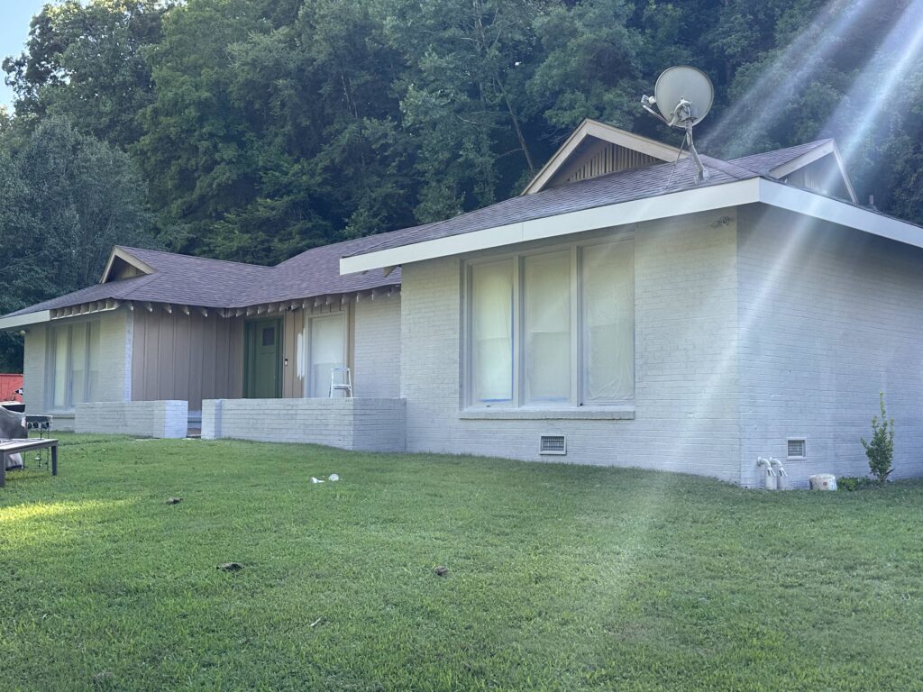 Residential home with a newly installed roof, featuring a combination of brown shingles and white brick exterior, situated on a green lawn, showcasing BisonWorks' commitment to quality roofing solutions.