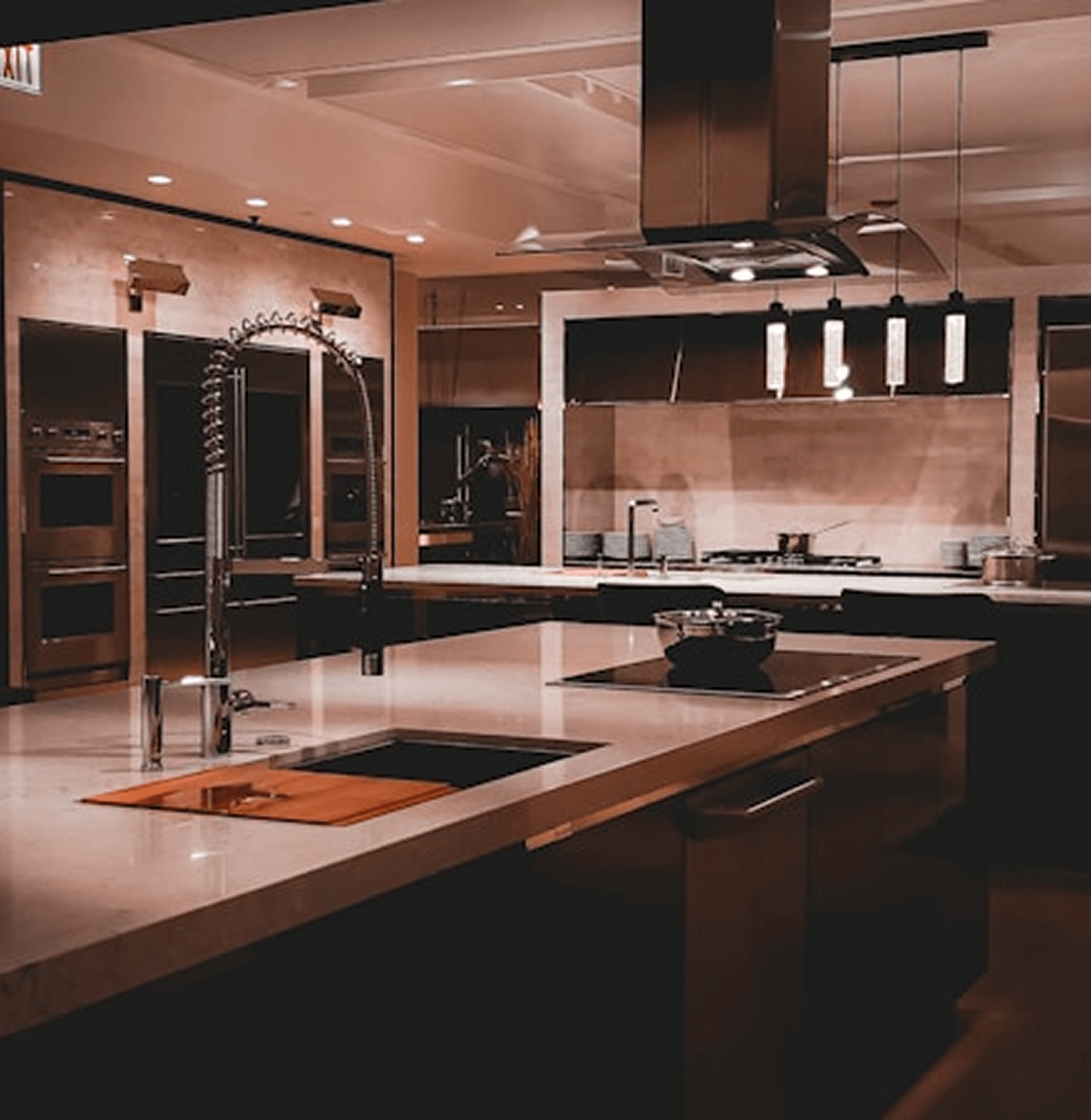 Modern kitchen with sleek design, featuring a large island, stainless steel appliances, and stylish pendant lighting, showcasing custom craftsmanship and functionality.