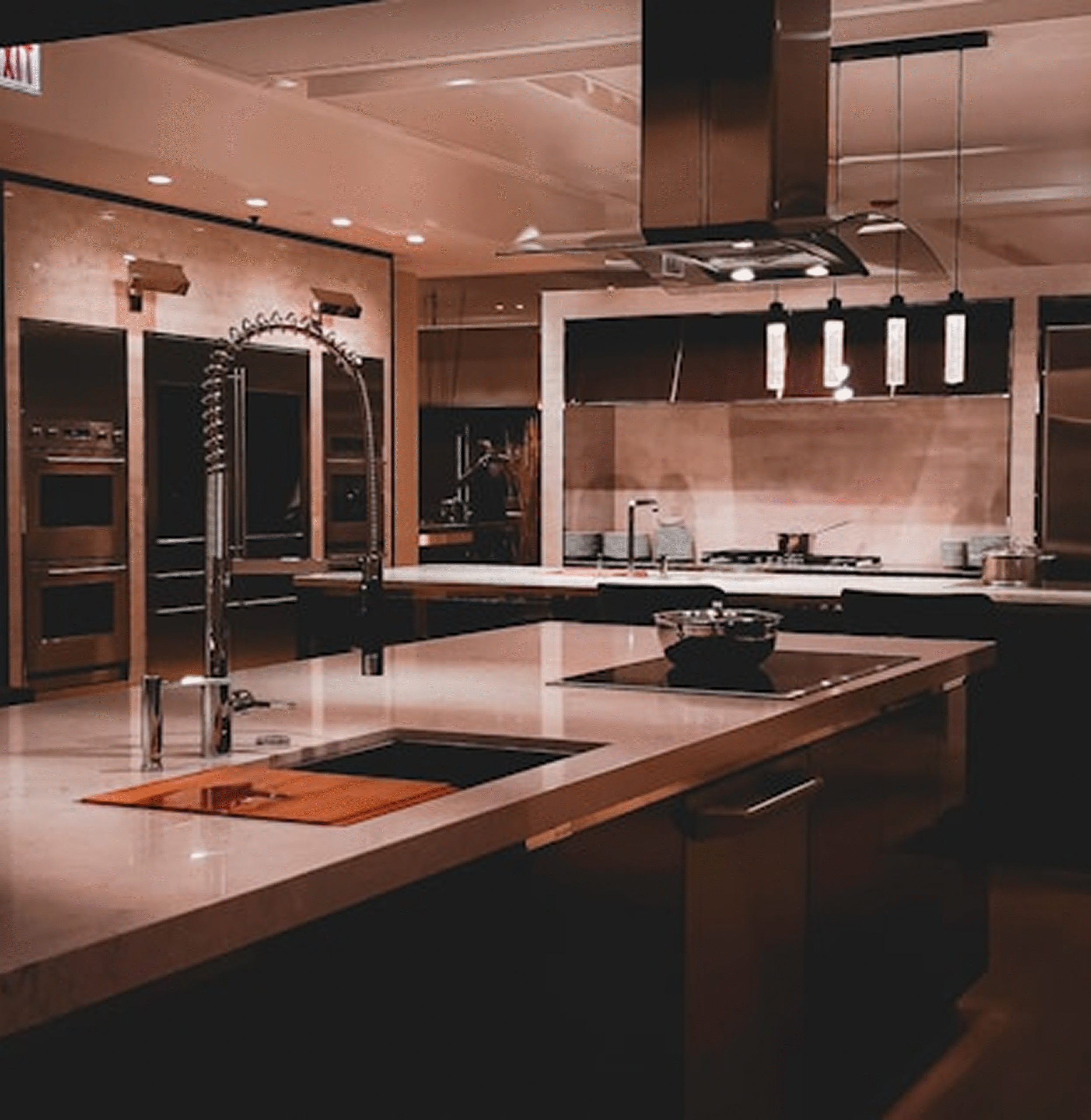 Modern kitchen interior featuring sleek countertops, stainless steel appliances, and stylish pendant lighting, emphasizing custom design and functionality for home improvement projects.